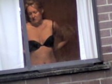 My sweet neighbor putting on her black bra in the window