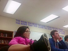 Geeky girl sits with legs on school desk