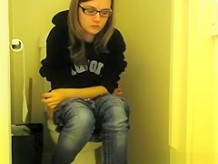 Girl in glasses pees in bathroom toilet