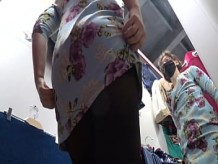 Una cámara oculta en un probador espía a una chica con un hermoso culo y hermosas piernas en pantimedias. Luego, un voyeur se asoma debajo de su falda en una tienda pública. Fetiche de pies amateur.