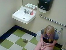 Chica rubia en Pees en un baño público
