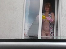 La sexy milf Frina en bata, sin bragas y sujetador, lava las ventanas del apartamento y no se avergüenza del taxista al azar en la calle que mira desde su auto. Desnudo en público. Desnudo en público. Desnudez pública. En público. Público. Milf de tetas n